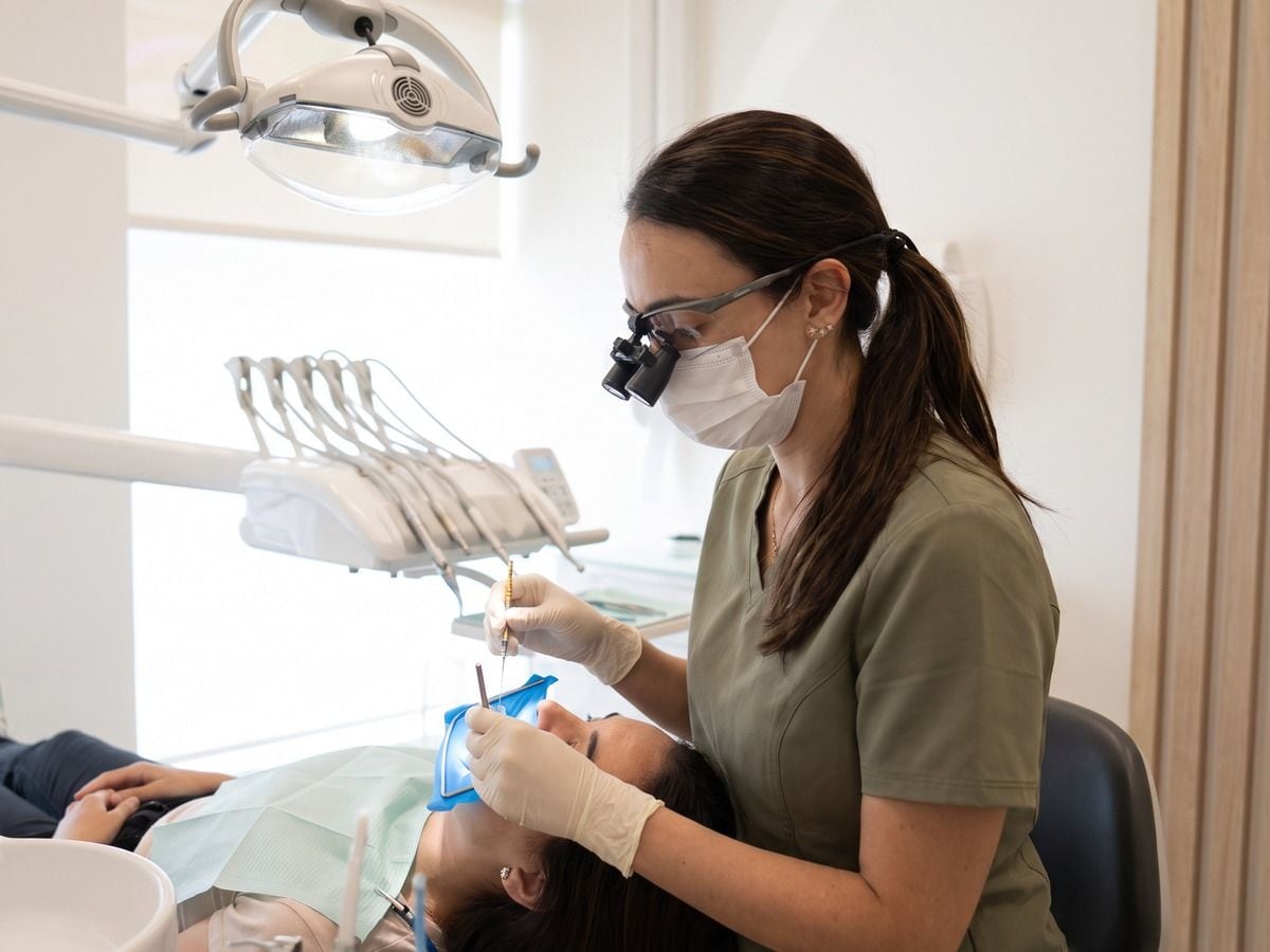 Recreación con IA: endodoncia con dique de goma y lupas de aumento